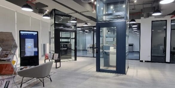 Cibes Dubai showroom interior with two demo home lifts in glass shafts, seating area, and displays.