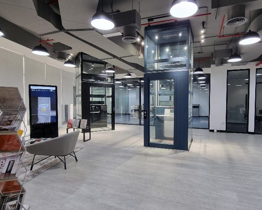Cibes Dubai showroom interior with two demo home lifts in glass shafts, seating area, and displays.
