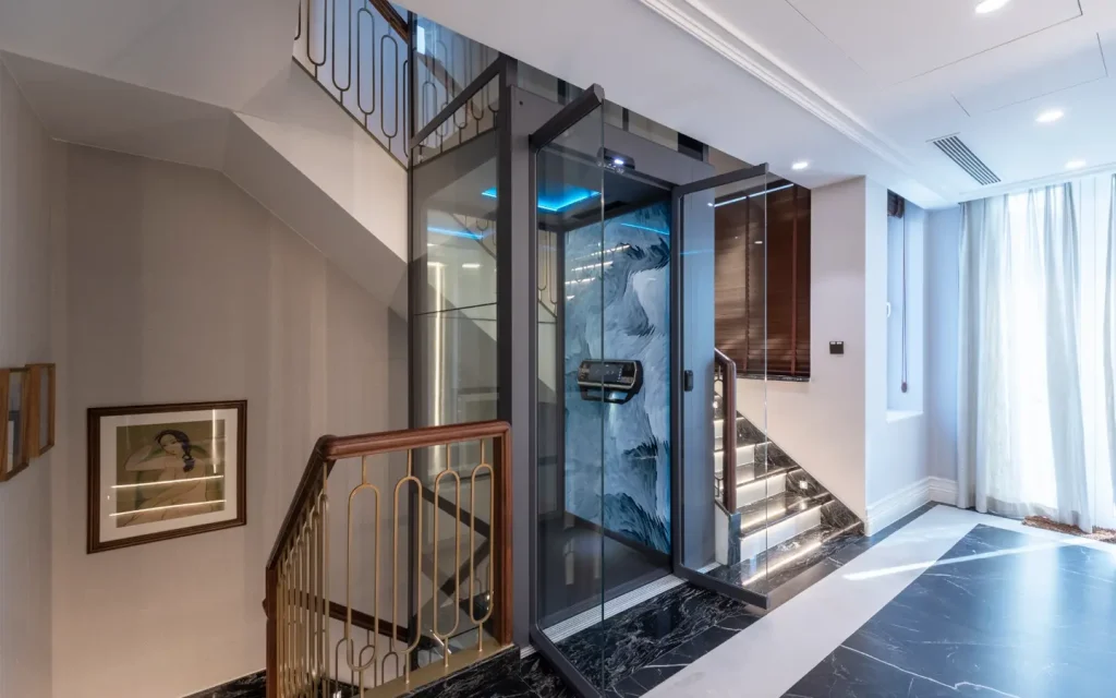 Luxury screw-driven home lift installed inside a modern villa, featuring a panoramic glass shaft and elegant interior finish.