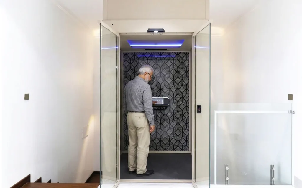 Homeowner using a cabin home lift with glass doors inside a UAE villa.