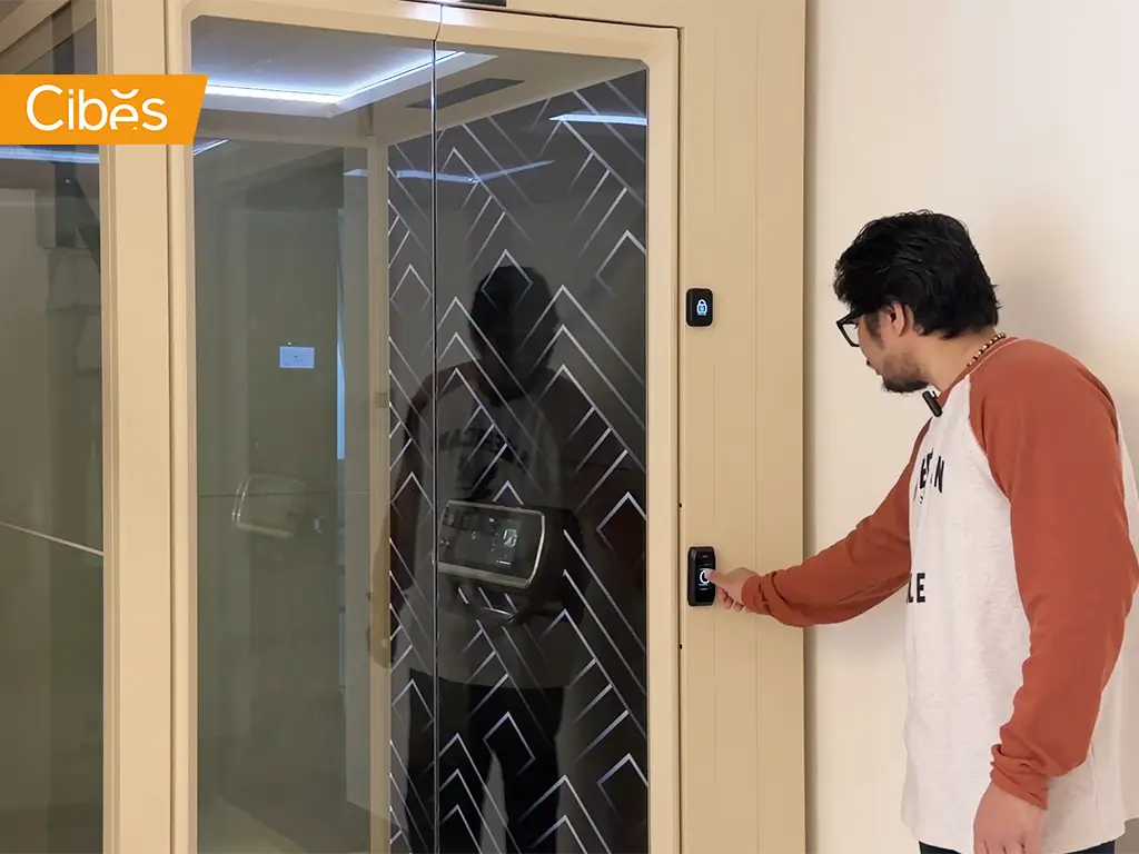 Homeowner using the external call button beside a Cibes V90 home lift with glass doors.